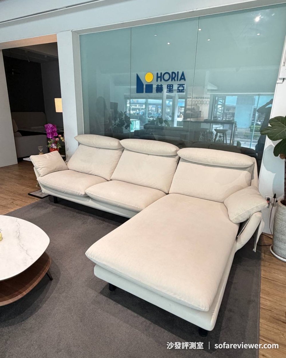 HORIA 赫里亞泰山創始店的米白色 L 型沙發與品牌玻璃牆